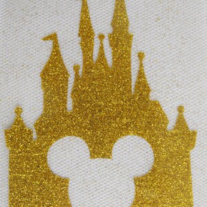 May include: Gold glitter iron-on design featuring a silhouette of the iconic Disney castle with Mickey Mouse ears in the front.