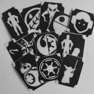 May include: A set of 12 black and white stencils featuring Star Wars characters and symbols. The stencils include Yoda, Darth Vader, R2-D2, a Stormtrooper, and the Rebel Alliance symbol.