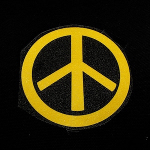 Könnte beinhalten: Ein gelbes Peace-Zeichen auf schwarzem Hintergrund.