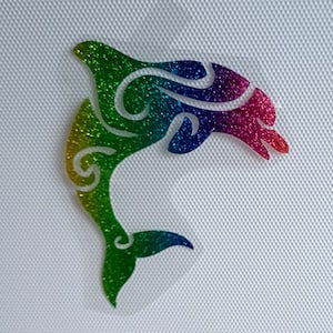 Peut inclure: Une silhouette de dauphin en paillettes arc-en-ciel, un design fantaisiste pour un projet d'artisanat ou de décoration intérieure.