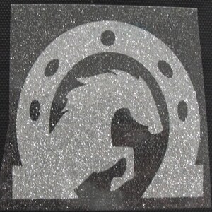 May include: A glittery silver and black graphic featuring a horseshoe shape with a stylized horse head silhouette inside. The design has a textured, sparkling appearance, suitable for crafts or apparel.