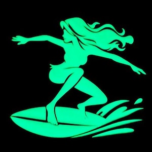 Op de afbeelding: Een groene silhouet van een persoon die surft op een golf. De persoon heeft lang haar en draagt een bikini-top. De golf breekt achter de persoon.