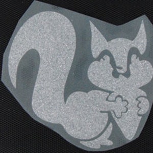 May include: A white, reflective, vinyl sticker of a cartoon squirrel holding a nut. The squirrel has a large, bushy tail and a friendly expression.