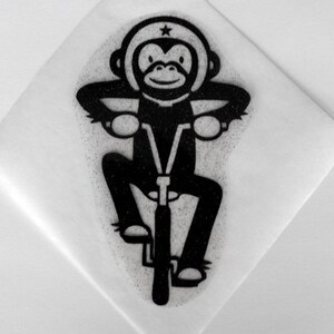 Può includere: Illustrazione in bianco e nero di una scimmia che indossa un casco con una stella in cima, che va in bicicletta.