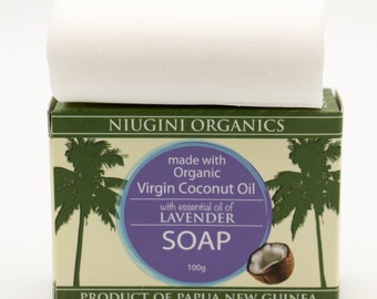May include: A white bar of soap with a purple label that reads "NIUGINI ORGANICS made with Organic Virgin Coconut Oil with essential oil of LAVENDER SOAP 100g PRODUCT OF PAPUA NEW GUINEA". The label has a green palm tree design and a coconut.