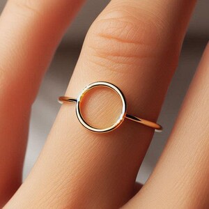 Puede incluir: Un anillo de oro con un diseño simple de círculo. El anillo es delgado y delicado, y el círculo está ligeramente elevado.