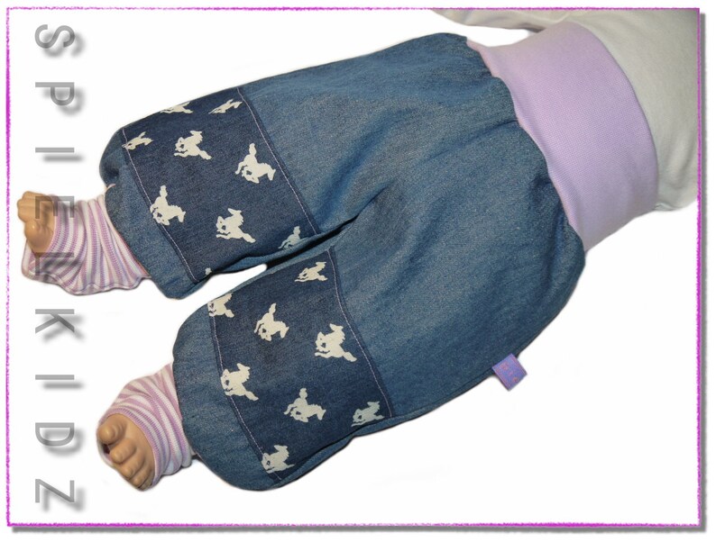 Pu&ograve; includere: Pantaloni per neonati in denim blu con stampa di coniglietto bianco e fascia in lavanda.