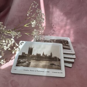 以下が含まれることがあります： ロンドンの国会議事堂の白黒写真がプリントされた白いコースターのセット。1908年頃の画像です。コースターは角が丸く、「London, Houses of Parliament, c.1908」の文字が印刷されています。