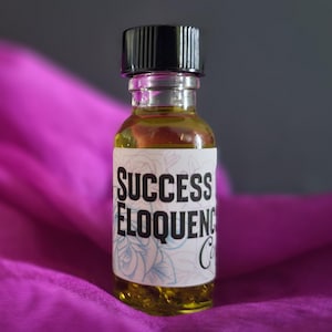 May include: A small glass bottle with a black cap filled with a yellow liquid. The bottle has a white label with the text "SUCCESS ELOQUENCE OIL" in black lettering.
