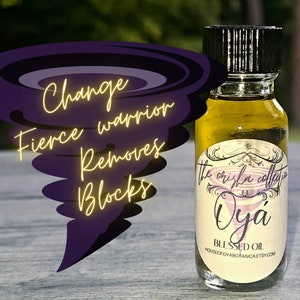 May include: A small glass bottle with a black cap filled with a yellow liquid. The label reads "The original collection, Oya, Blessed Oil, HouseofOyabotanica.etsy.com". The bottle is sitting on a wooden surface. The text "Change, Fierce warrior, Removes blocks" is written in yellow on a purple background.