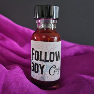Può includere: Una piccola bottiglia di vetro con un tappo nero riempita di un liquido scuro. La bottiglia ha un'etichetta bianca con il testo "FOLLOW BOY Conj" stampato su di essa.