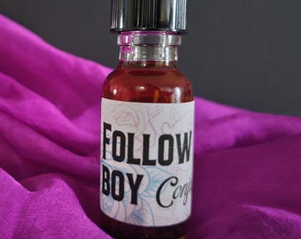 May include: A small glass bottle with a black cap filled with a dark liquid. The bottle has a white label with the text "FOLLOW BOY Conj" printed on it.