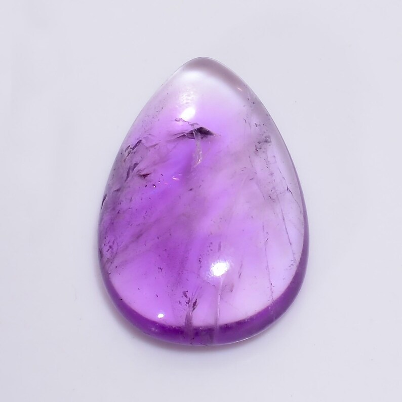 May include: A teardrop-shaped amethyst gemstone with a light purple hue and a translucent appearance.