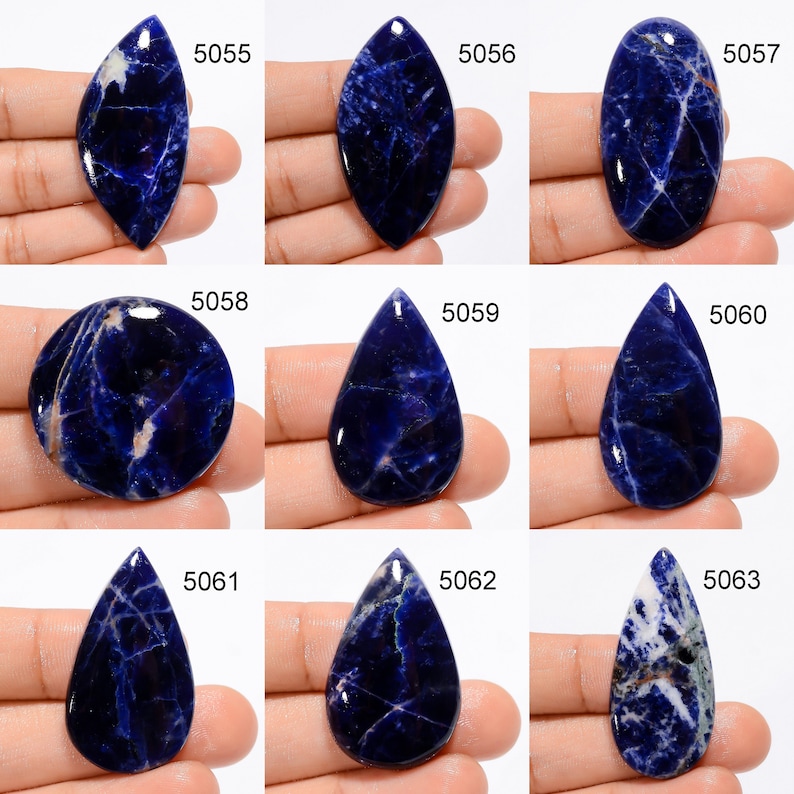 Op de afbeelding: Twaalf cabochon geslepen blauwe en witte sodaliet edelstenen, elk met een uniek patroon en vorm. De stenen zijn genummerd van 5055 tot en met 5063.