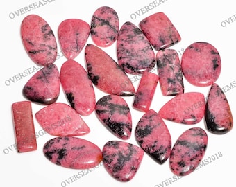 Puede incluir: Una colección de 17 cabujones de piedras preciosas rosas y negras. Las piedras son de varias formas y tamaños, incluyendo ovaladas, en forma de lágrima y rectangulares. Las piedras están pulidas y tienen un acabado liso y brillante.