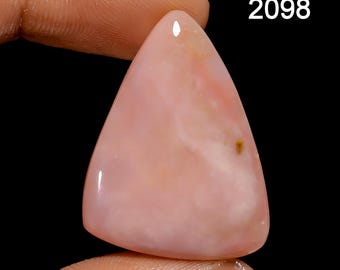 Pode incluir: Um cabochão de opala rosa com forma triangular e uma superfície lisa e polida. A pedra tem uma cor rosa claro com inclusões brancas e marrons.