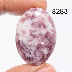 May include: A pink and white oval shaped Lepidolite gemstone with a swirling pattern. 8283
