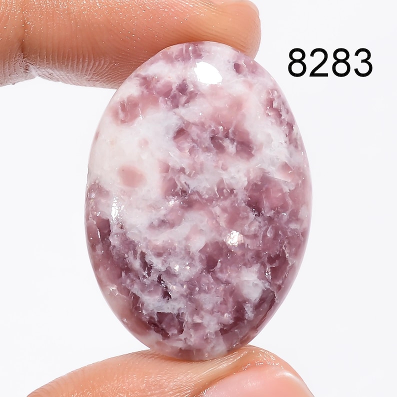 May include: A pink and white oval shaped Lepidolite gemstone with a swirling pattern. 8283