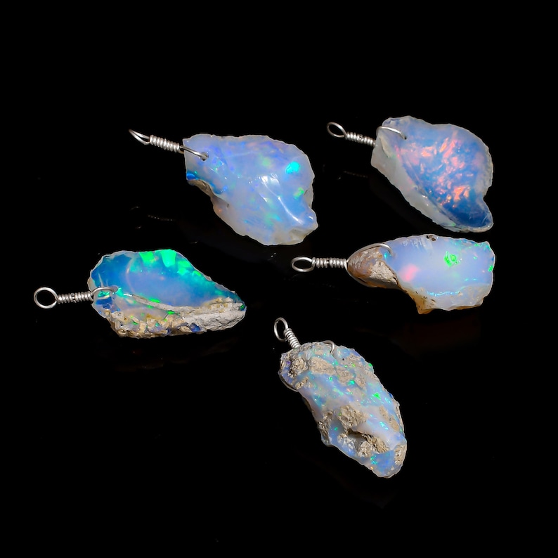 May include: Five raw opal pendants with silver wire loops. The opals are a milky white with flashes of blue, green, and pink.
