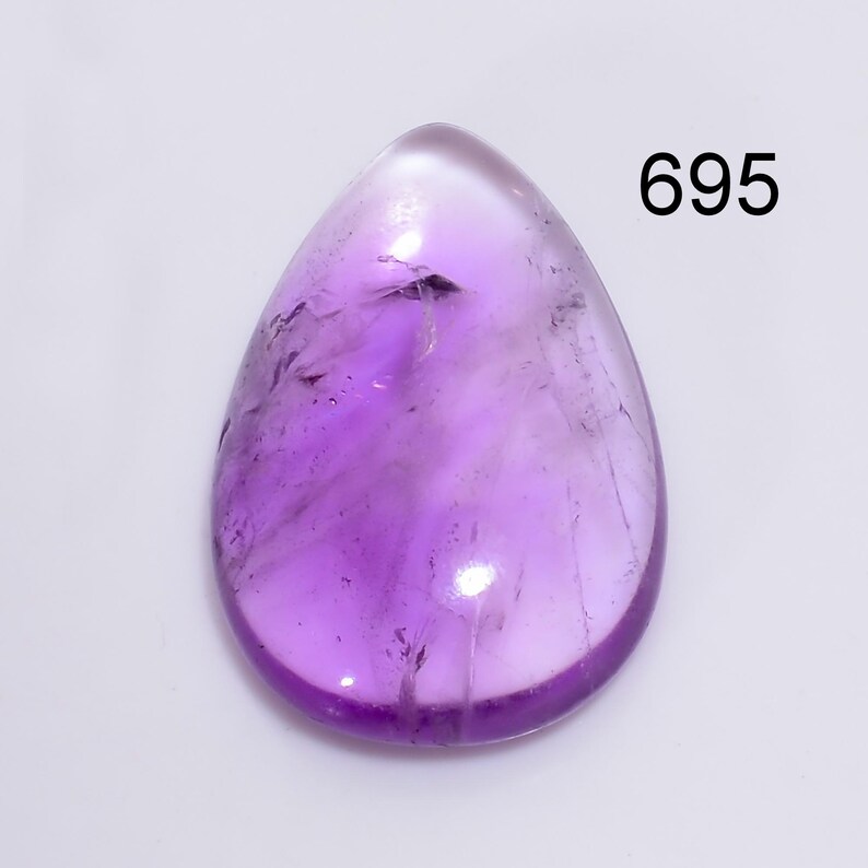 May include: A purple amethyst gemstone cabochon, shaped like a teardrop, with a smooth, polished surface. The stone is translucent and has a light purple hue. The image is labelled with the number 695.