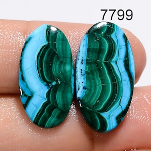 May include: Pair of oval-shaped cabochon gemstones with a blue and green swirling pattern. The stones are approximately 1 inch in length.