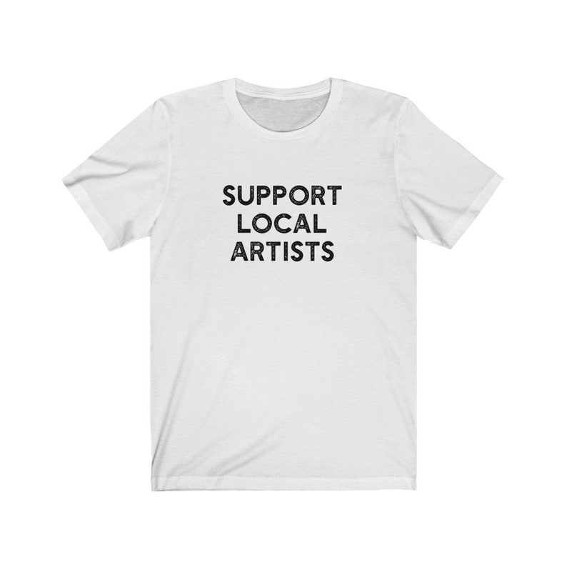 May include: White t-shirt with the text "SUPPORT LOCAL ARTISTS" printed in black.