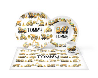 May include: A white dinnerware set including a plate, a bowl, and a mug, plus a rectangular placemat. Each item features a repeating pattern of yellow construction vehicles, orange traffic cones, and stop signs, with the name TOMMY printed.