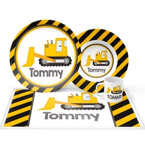 May include: A dinnerware set consisting of two round plates, a mug, and a rectangular placemat. Each item features a yellow bulldozer graphic, black and yellow diagonal hazard stripes, and the name Tommy printed in a gray, textured font.