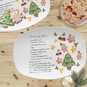 May include: An oval white ceramic serving platter featuring a printed recipe for Chocolate Chip Cookies in black script. The platter is decorated with watercolor illustrations of Christmas trees, gingerbread people, stars, and holly berries.