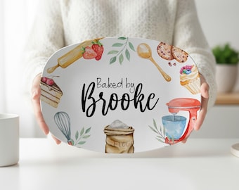 May include: An oval white serving platter featuring a watercolor illustration of baking tools and ingredients, including a rolling pin, whisk, flour sack, and stand mixer. The text "Baked by Brooke" is printed in black in the center.