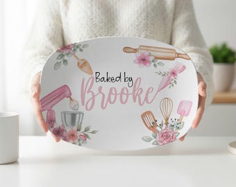 May include: An oval white serving platter featuring a watercolor illustration of baking tools including a pink stand mixer, a rolling pin, a whisk, and spatulas. The text "Baked by Brooke" is printed in black and pink script in the center.
