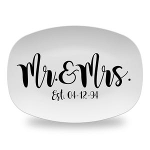 May include: White oval serving platter with black calligraphy that reads "Mr. & Mrs. Est. 04-12-94".