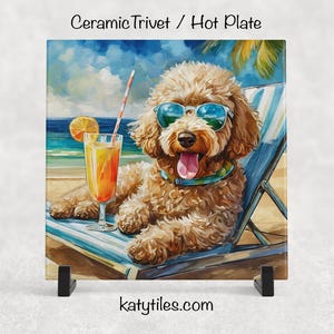 May include: Ceramic trivet featuring a poodle wearing sunglasses and relaxing on a beach chair with a cocktail. The artwork has a watercolor style, with a blue ocean and sky background. The trivet is square and has the text "Ceramic Trivet / Hot Plate".