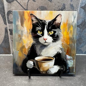 May include: A black and white cat with yellow eyes is holding a brown coffee mug. The cat is painted on a ceramic tile with a yellow, orange, and blue background.