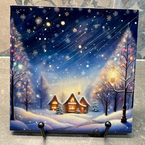 May include: A snowy winter scene with a cozy cabin lit up with warm yellow lights. The cabin is surrounded by snow-covered trees with twinkling lights. The sky is a deep blue with falling snow and stars.