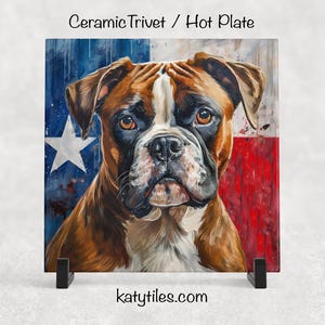 May include: Square ceramic hot plate with a Boxer dog portrait set against a Texas flag design. The dog has brown and white fur. The trivet rests on a black stand. The text "Ceramic Trivet / Hot Plate" and "katytiles.com" are visible.