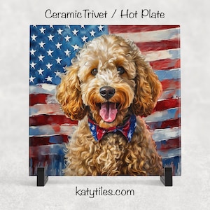 May include: Square ceramic trivet featuring a golden doodle dog with a red, white, and blue bow tie, set against a backdrop of the American flag. The text "Ceramic Trivet / Hot Plate" is at the top. The website "katytiles.com" is at the bottom.