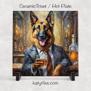 May include: Square ceramic hot plate featuring a painting of a German Shepherd in a suit, holding a whiskey. The background is a bar scene with bottles and warm tones. Text at the top reads "Ceramic Trivet / Hot Plate".