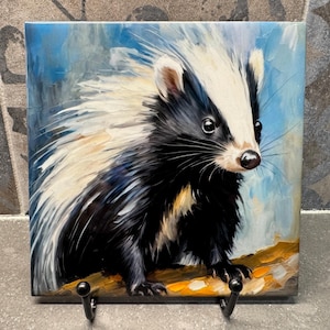 May include: Square ceramic tile featuring a detailed painting of a badger. The badger has black and white fur with a white stripe on its face. The background is a blend of blue and white, and the badger is perched on a branch.