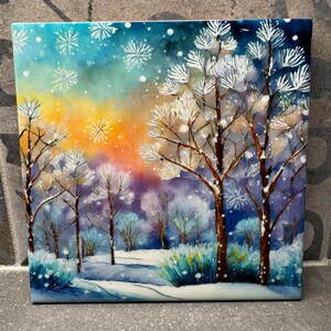 Puede incluir: Una pintura de acuarela de una escena de invierno nevada con árboles cubiertos de escarcha y un camino que conduce a través del bosque. El cielo es de un azul vibrante con toques de amarillo y naranja, y caen copos de nieve.