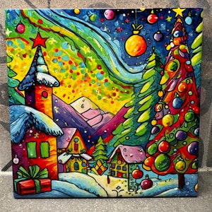 May include: A colorful painting of a winter village scene with a large Christmas tree, houses, and a snowy mountain range in the background. The sky is a vibrant blue with swirling clouds and stars. The painting is done in a whimsical style with bright colors and bold lines.