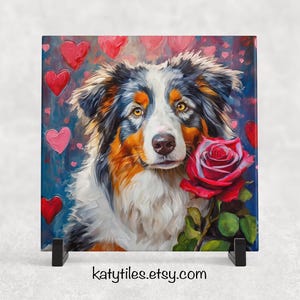 May include: A colourful painting of an Australian Shepherd dog with a red rose in its mouth. The background is a blue and pink abstract design with hearts.