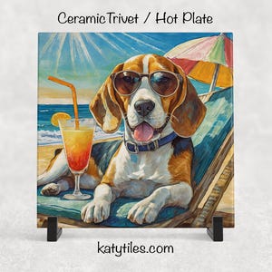 May include: Ceramic trivet featuring a beagle wearing sunglasses, relaxing on a beach chair with a cocktail. The artwork has a sunny beach scene with a colorful umbrella and ocean in the background. The trivet is square and has the text "katytiles.com".