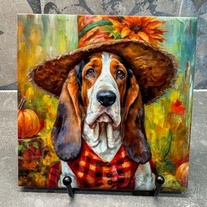 Puede incluir: Una pintura de un perro basset hound con un sombrero de paja con un girasol en la parte superior. El perro lleva una camisa de cuadros rojos y negros y está rodeado de follaje otoñal.