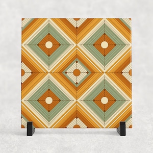 May include: A square ceramic tile with a geometric pattern in shades of orange, yellow, green, and white. The pattern is made up of overlapping squares and diamonds.