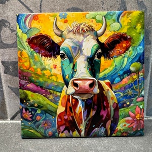 May include: Square canvas art depicting a colourful cow portrait. The cow has a white face with blue, green, and brown markings. The background is a vibrant mix of yellow, green, and blue with floral and abstract elements. A unique piece of artwork.