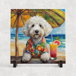 May include: A square ceramic tile featuring a white dog wearing a colorful Hawaiian shirt, sitting on a beach under a yellow and green umbrella. A tropical drink with a straw and fruit garnish sits nearby. The background shows the ocean and sky.