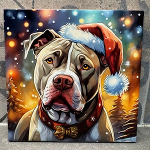 May include: A brown and white pit bull dog wearing a red Santa hat with a white pom-pom. The dog is wearing a red collar with a gold bow tie. The background is a blurred image of a snowy forest with twinkling lights.