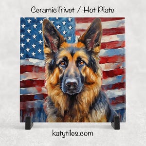 May include: Ceramic trivet or hot plate with a German Shepherd dog design set against the American flag. The dog has brown and black fur, with a focused gaze. The flag's red and white stripes and blue star field are visible.