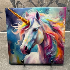 May include: A colorful painting of a white unicorn with a gold horn and a rainbow mane. The background is a blue and purple watercolor wash.